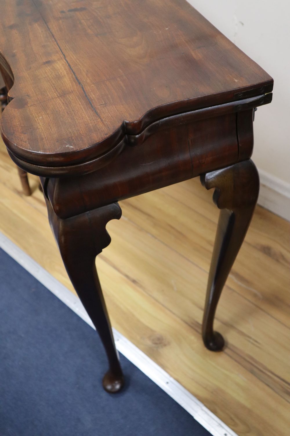 A George I red walnut serpentine top card table, with dished corners, frieze drawer and slender cabriole legs, width 82cm